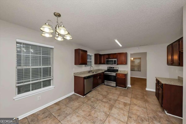 kitchen with appliances with stainless steel finishes, a textured ceiling, pendant lighting, and a notable chandelier