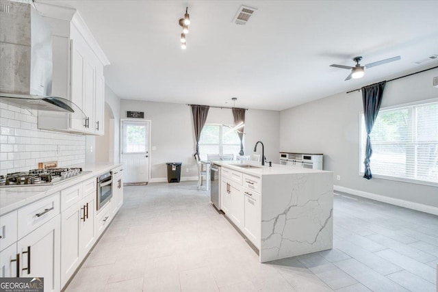 kitchen featuring a center island with sink, white cabinetry, sink, and ceiling fan