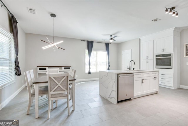 kitchen featuring ceiling fan with notable chandelier, white cabinets, appliances with stainless steel finishes, and sink