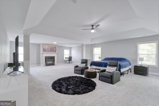 carpeted bedroom with a tray ceiling, ceiling fan, and ornate columns