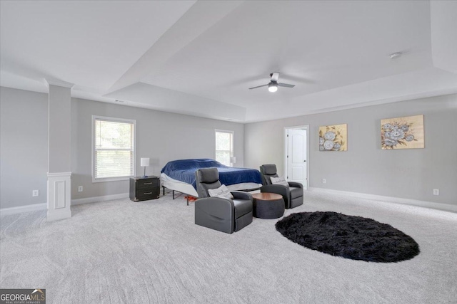 carpeted living room with decorative columns, a tray ceiling, and ceiling fan