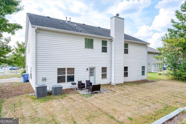 rear view of property featuring a lawn, cooling unit, and a patio