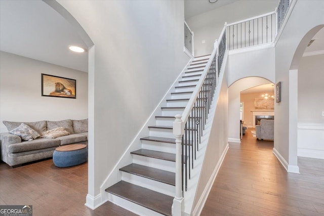 stairway with hardwood / wood-style flooring and a towering ceiling