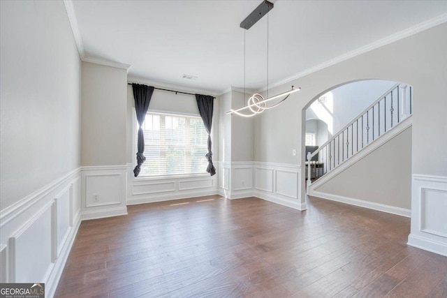 spare room with ornamental molding, a notable chandelier, and dark wood-type flooring