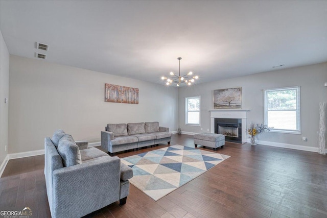 living room featuring a chandelier, plenty of natural light, and dark wood-type flooring