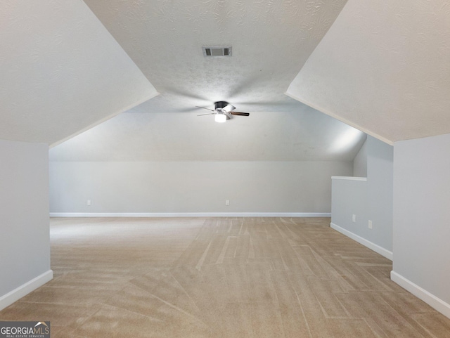 additional living space featuring a textured ceiling, light colored carpet, and lofted ceiling