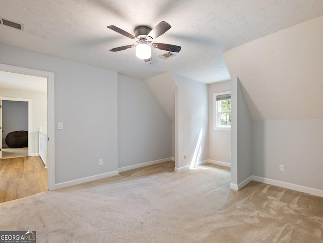 additional living space featuring lofted ceiling, light carpet, ceiling fan, and a textured ceiling