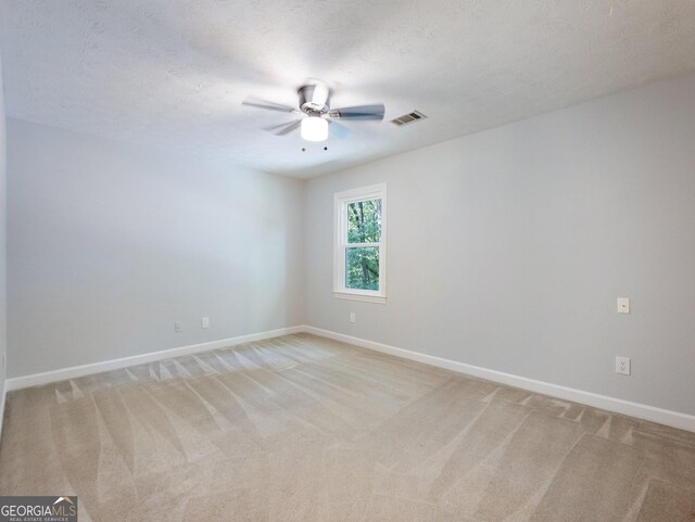 spare room with light carpet, ceiling fan, and a textured ceiling