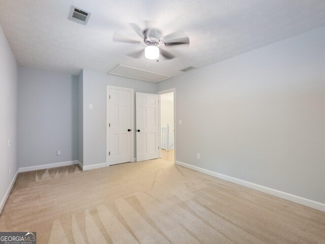 unfurnished bedroom with ceiling fan, light carpet, and a textured ceiling