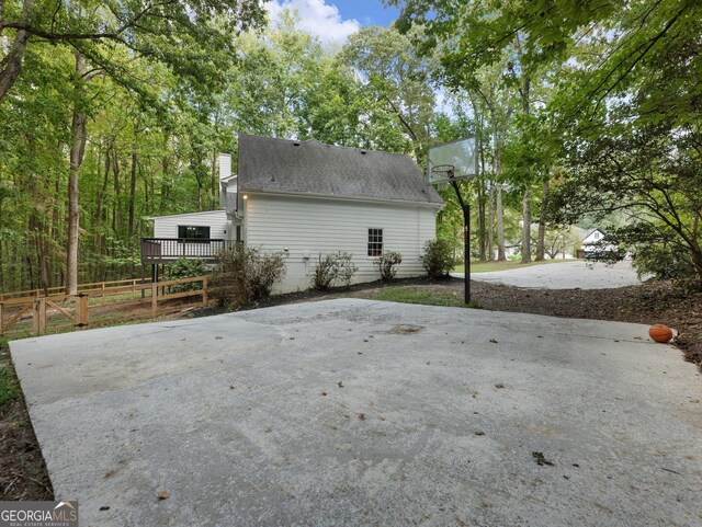 view of home's exterior with basketball court and a deck