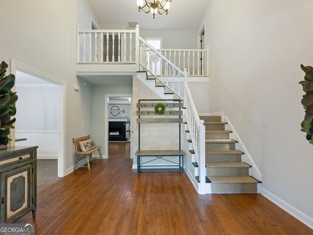 stairway featuring hardwood / wood-style floors, a notable chandelier, and a high ceiling