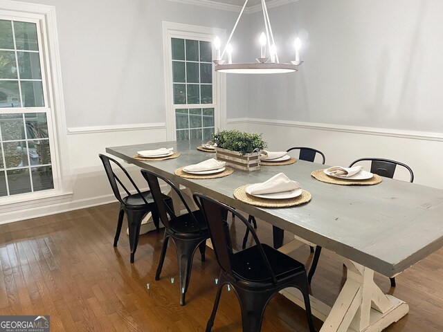 dining room featuring ornamental molding, dark wood-type flooring, and an inviting chandelier