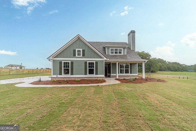 rear view of property featuring a yard and a porch