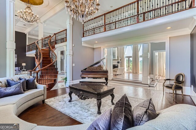 9620 Cedar Grove Rd, Fairburn, GA 30213 - living area featuring decorative columns, a towering ceiling, a chandelier, crown molding, and wood finished floors