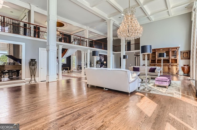 9620 Cedar Grove Rd, Fairburn, GA 30213 - living room featuring a high ceiling, decorative columns, wood finished floors, a chandelier, and beam ceiling