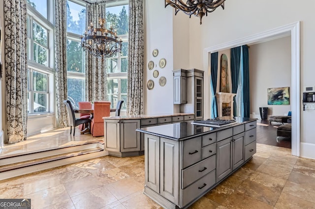 9620 Cedar Grove Rd, Fairburn, GA 30213 - kitchen featuring gray cabinets, a chandelier, a towering ceiling, a center island, and light stone finish flooring