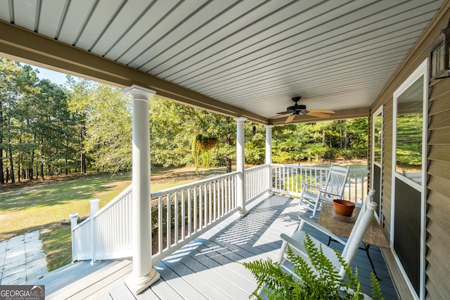 wooden terrace featuring ceiling fan and a lawn