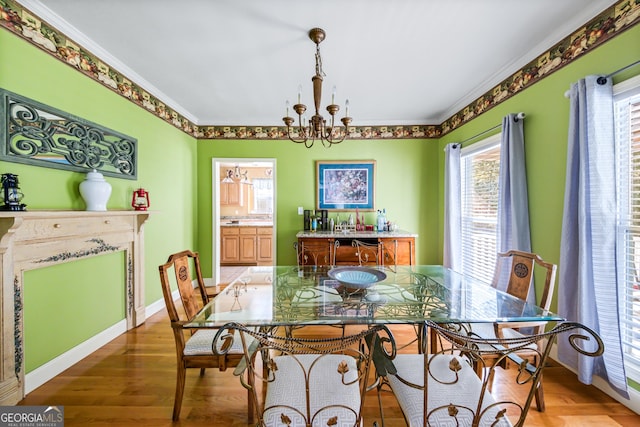 dining space with wood-type flooring, a notable chandelier, and ornamental molding