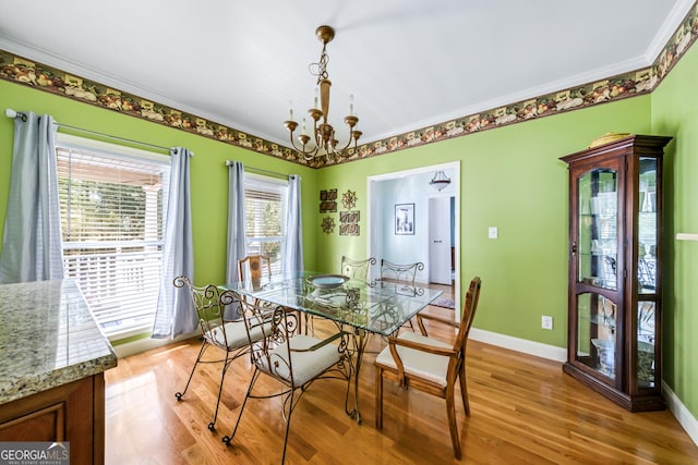 dining room with light hardwood / wood-style floors, ornamental molding, and an inviting chandelier