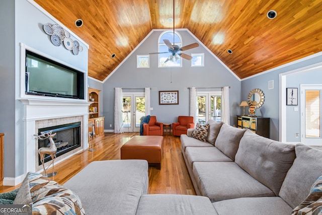 living room with wood ceiling, a tiled fireplace, french doors, and light wood-type flooring