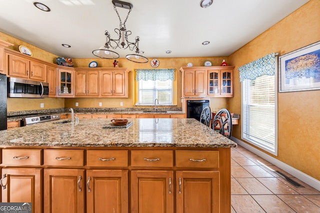 kitchen with decorative light fixtures, sink, light tile patterned flooring, and an island with sink