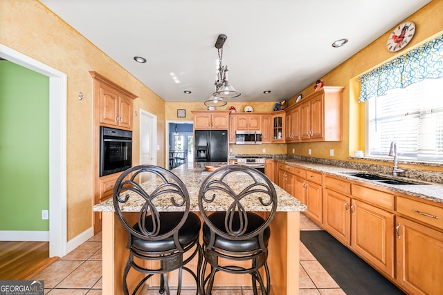 kitchen featuring black appliances, a kitchen island, light tile patterned floors, and sink