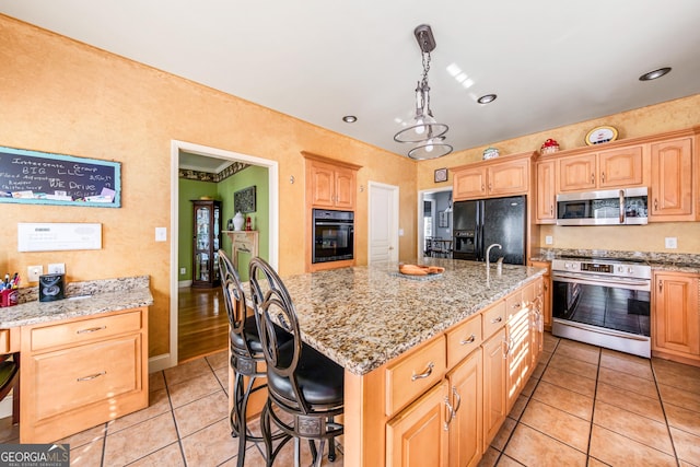 kitchen with decorative light fixtures, black appliances, light tile patterned floors, and an island with sink