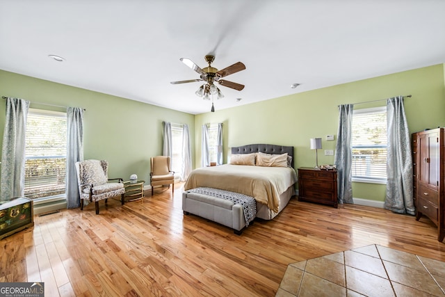 bedroom with ceiling fan, light hardwood / wood-style floors, and multiple windows