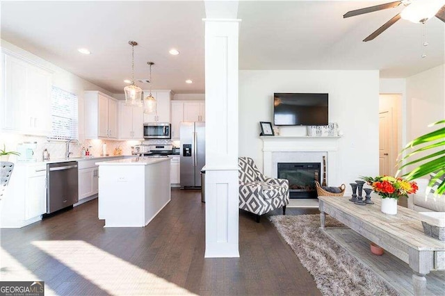 kitchen with hanging light fixtures, a center island, dark wood-type flooring, and stainless steel appliances