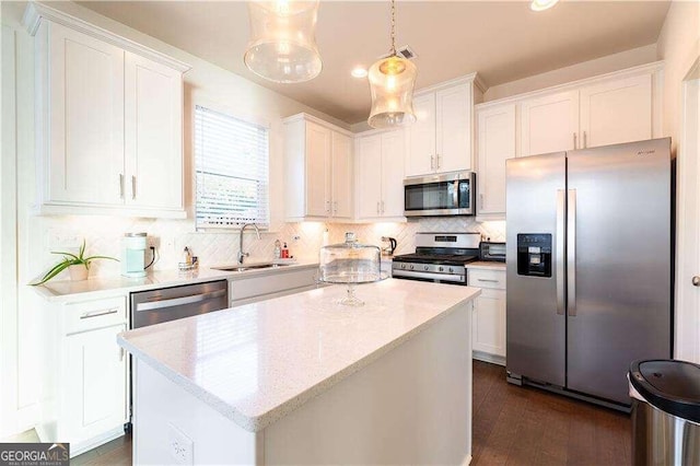 kitchen featuring pendant lighting, appliances with stainless steel finishes, white cabinets, and a kitchen island