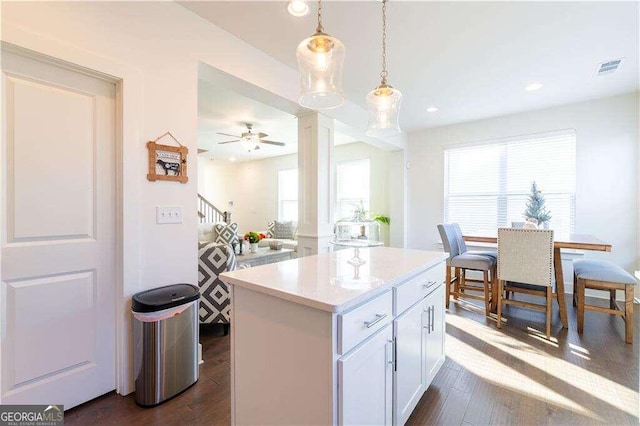 kitchen with ceiling fan, white cabinets, decorative light fixtures, a center island, and dark hardwood / wood-style flooring