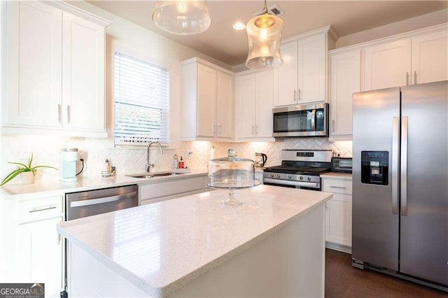 kitchen featuring appliances with stainless steel finishes, white cabinetry, sink, and decorative light fixtures