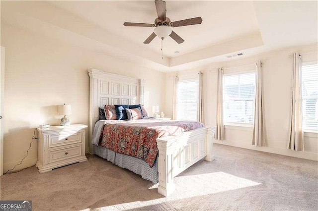 carpeted bedroom with a tray ceiling and ceiling fan