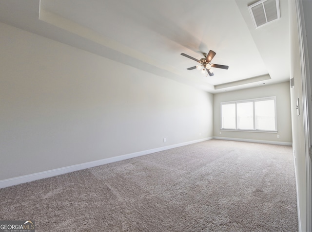 unfurnished room with ceiling fan, a raised ceiling, and carpet flooring