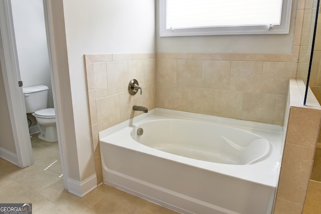 bathroom with a tub to relax in, tile patterned flooring, and toilet