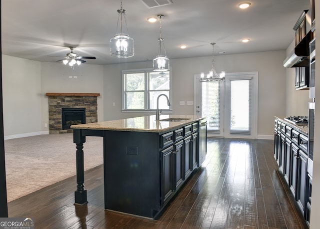 kitchen featuring a fireplace, sink, an island with sink, and a wealth of natural light