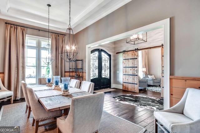 dining area featuring an inviting chandelier, a raised ceiling, dark hardwood / wood-style floors, and a barn door