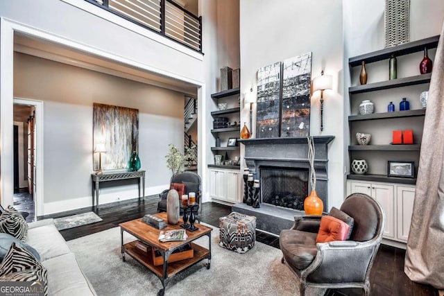 living room with a high ceiling, a fireplace, dark hardwood / wood-style floors, and built in features