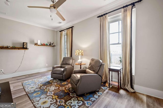 sitting room with wood-type flooring, crown molding, and ceiling fan