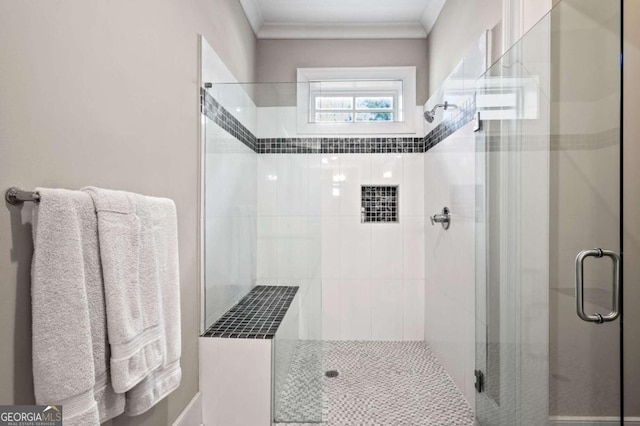 bathroom with a shower with shower door and ornamental molding