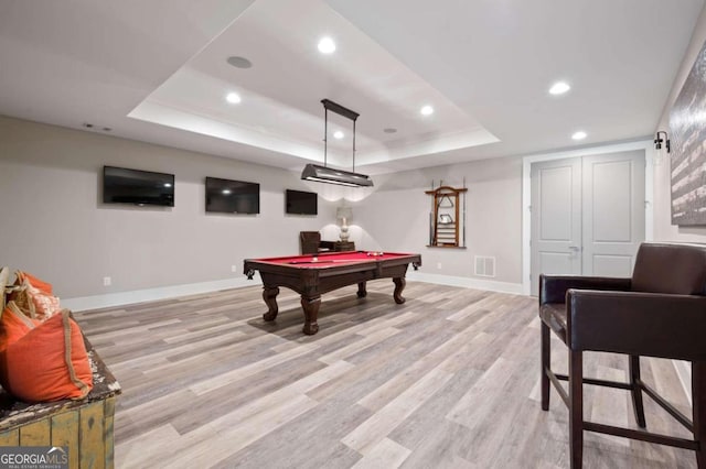 recreation room featuring pool table, light hardwood / wood-style floors, and a tray ceiling