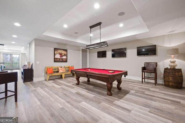 rec room with light wood-type flooring, pool table, and a tray ceiling