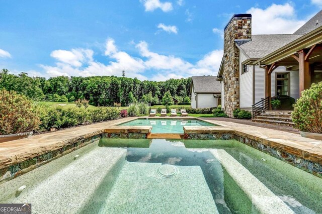 view of pool with an in ground hot tub and a patio area