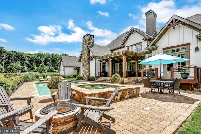 view of patio with an in ground hot tub and a fire pit