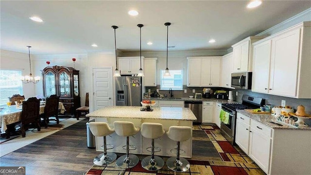 kitchen with pendant lighting, a kitchen island, appliances with stainless steel finishes, and a wealth of natural light