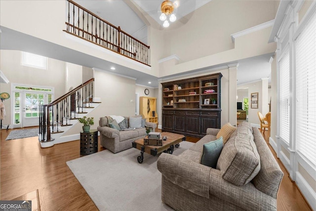 living room featuring ceiling fan, french doors, a high ceiling, wood-type flooring, and ornamental molding