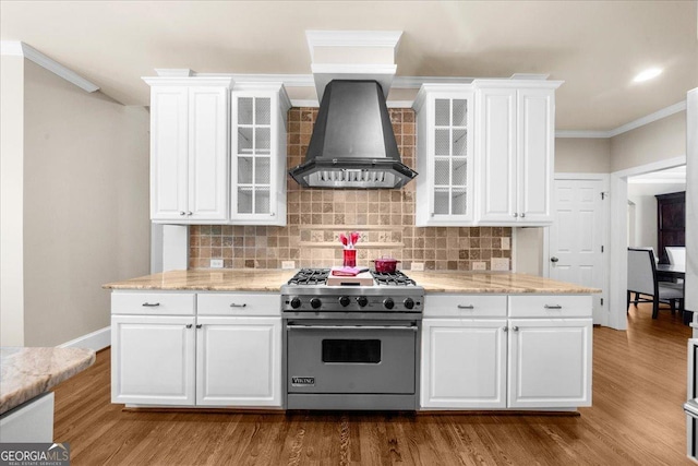 kitchen with decorative backsplash, stainless steel range, white cabinets, and wall chimney range hood