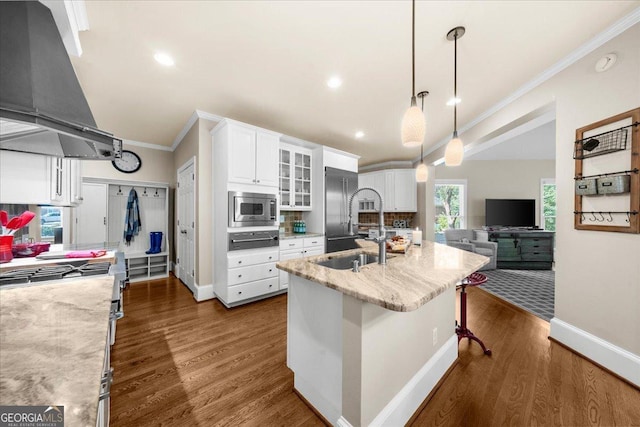 kitchen with tasteful backsplash, range hood, pendant lighting, a kitchen island with sink, and white cabinets