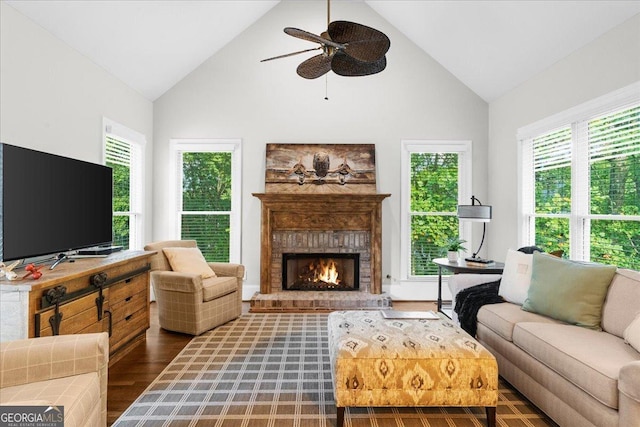 living room with ceiling fan, a fireplace, high vaulted ceiling, and dark wood-type flooring