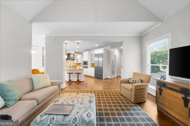 living room with hardwood / wood-style floors, vaulted ceiling, and ornamental molding